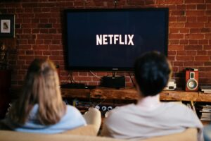 Two people sitting on the couch watching television